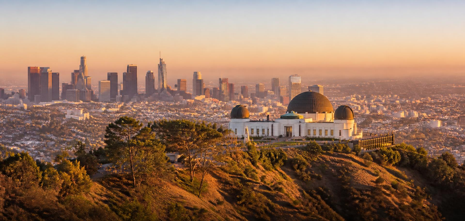 Griffith Observatory at golden hour with the downtown Los Angeles skyline behind it